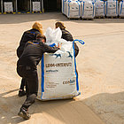 Big Bag Lehmputz von drei Personen über den Platz gezogen