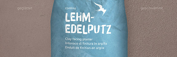 Lehm-Edelputz Ardesia conluto Lehm-Edelputz im Sack (Farbton Ardesia) vor Wandausschnitt im selben Farbton