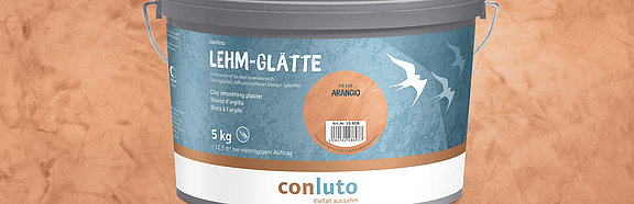conluto Lehm-Glätte im Eimer (Farbton Arancio) vor Wandausschnitt im selben Farbton